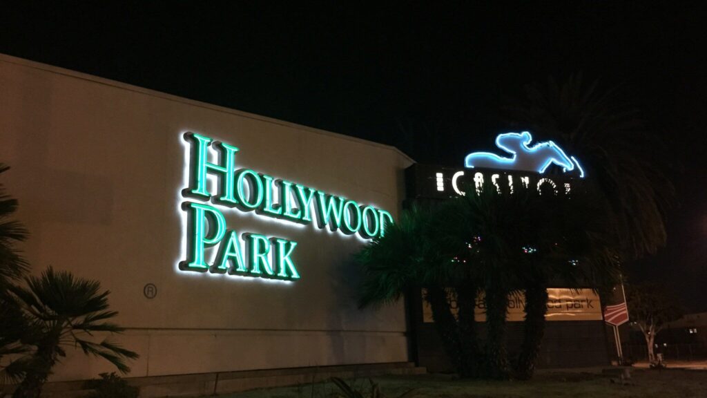 夜に光るHOLLYWOOD PARKの看板と、馬と騎手のネオン