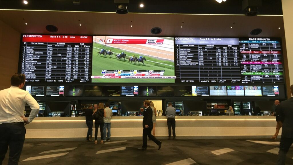 馬券売り場の後ろに並ぶ他場のレース中継スクリーン